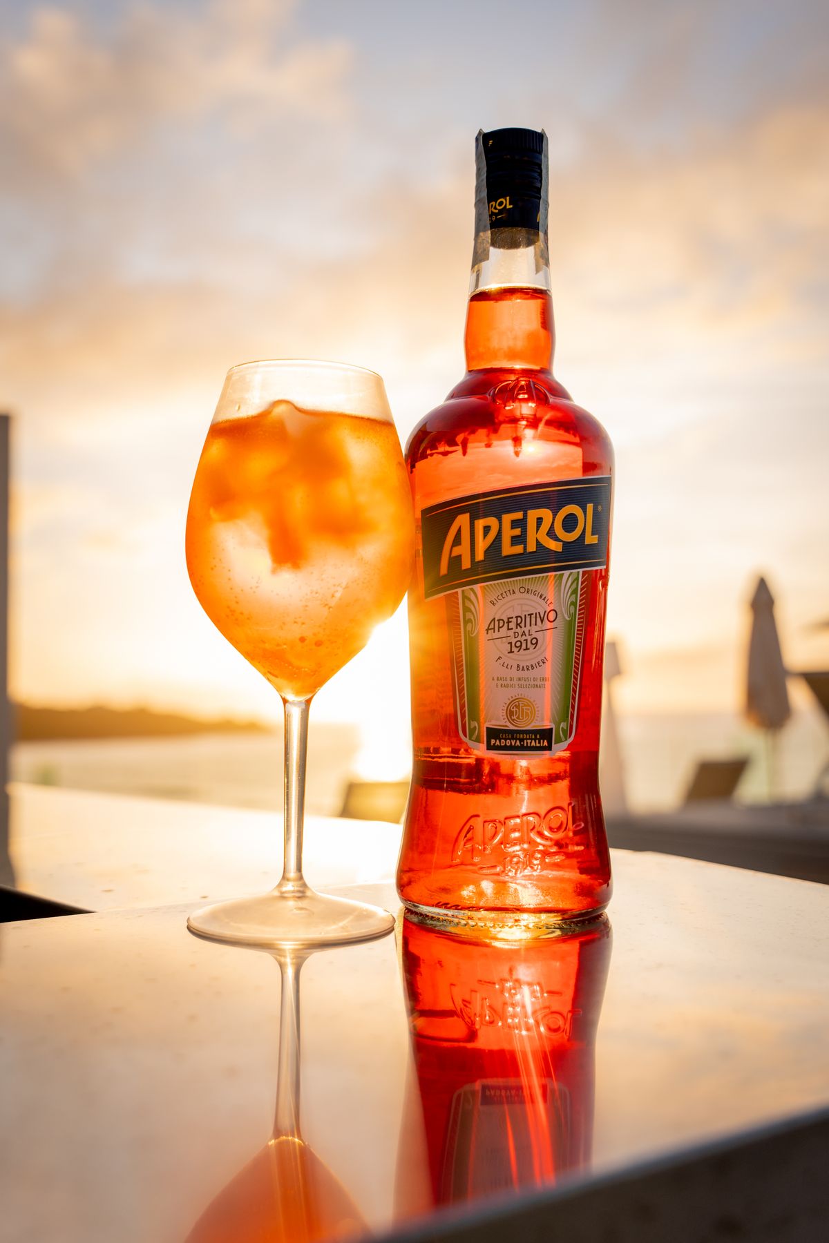 Spritz e bottiglia di Aperol controluce al tramonto
