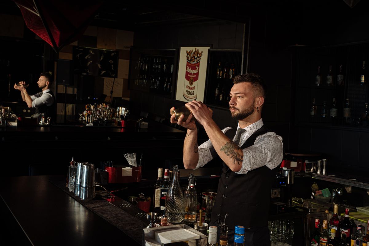 Barman che shakera un cocktail al bancone