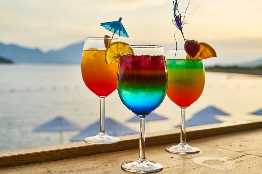 Tre cocktail colorati con guarnizioni sul mare
