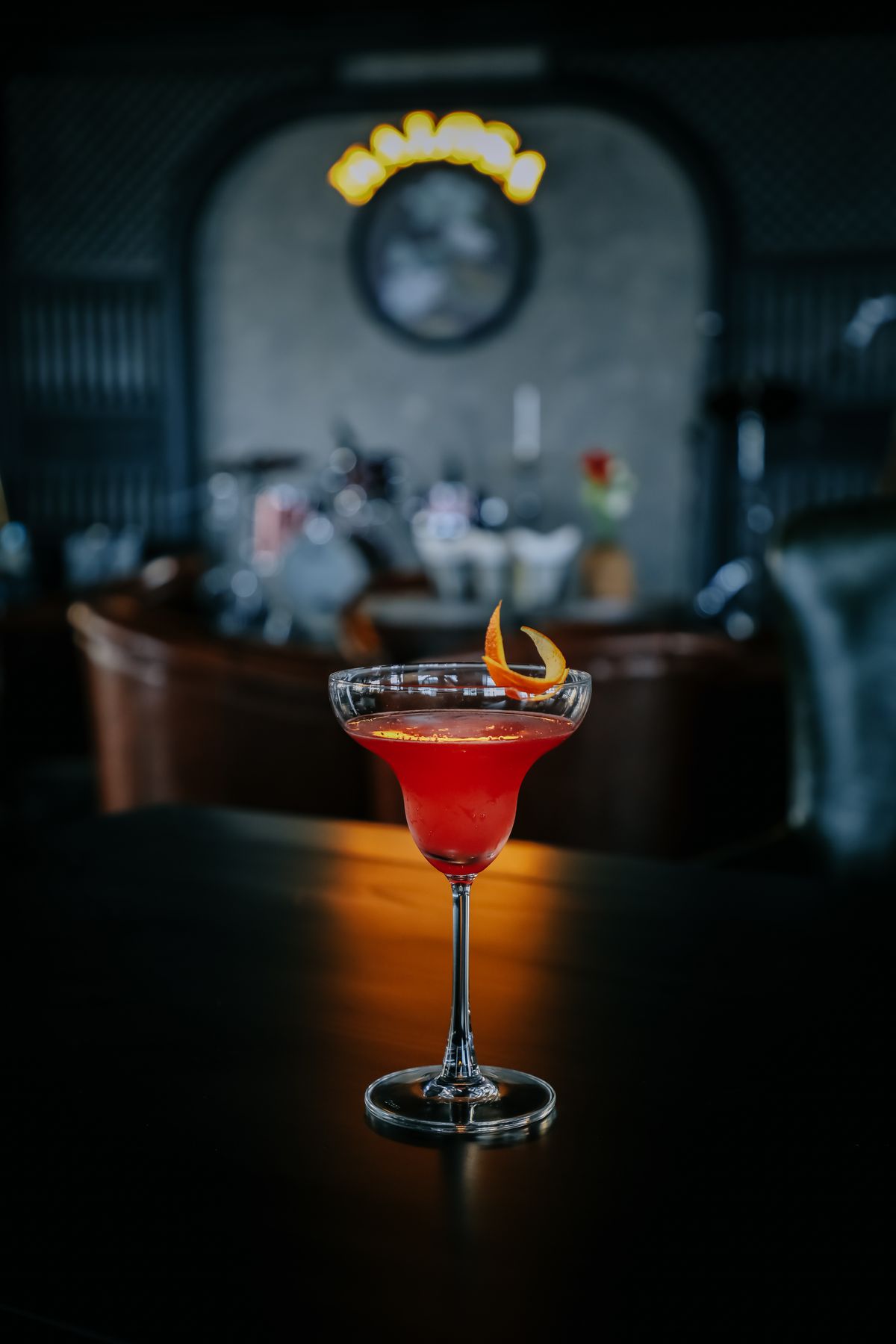 Cocktail rosso con scorza d'arancia in una sala soffusa